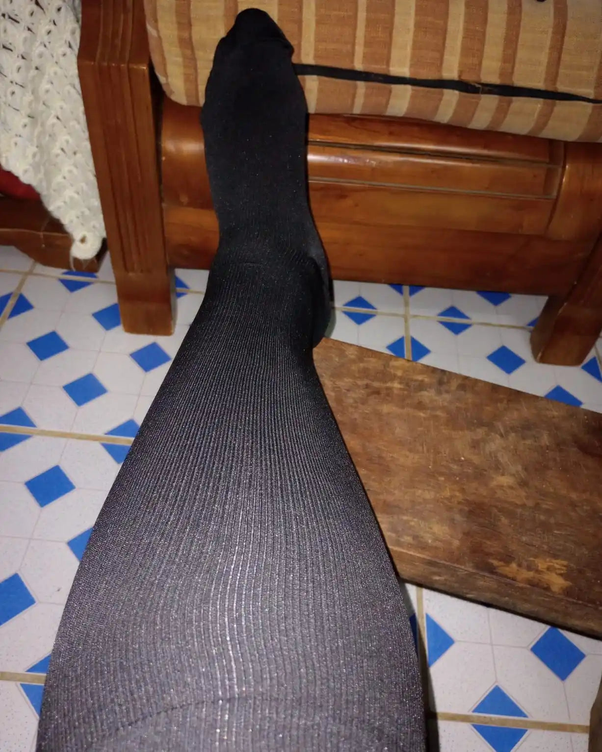 Une jambe d'une personne couverte de collants ou de bas noirs, côtelés.