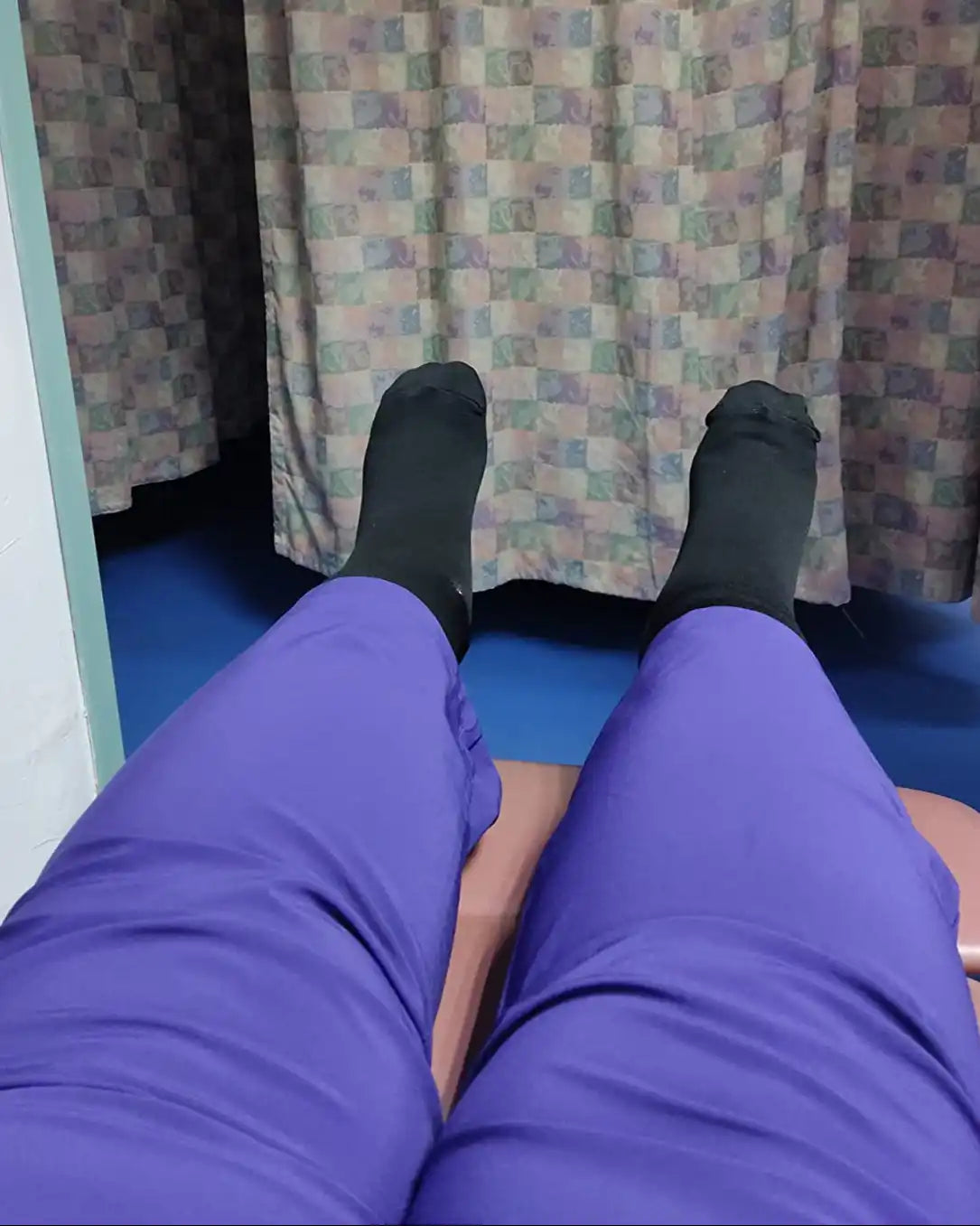 Les jambes d'une personne vêtues de pantalons violets et de chaussettes noires.