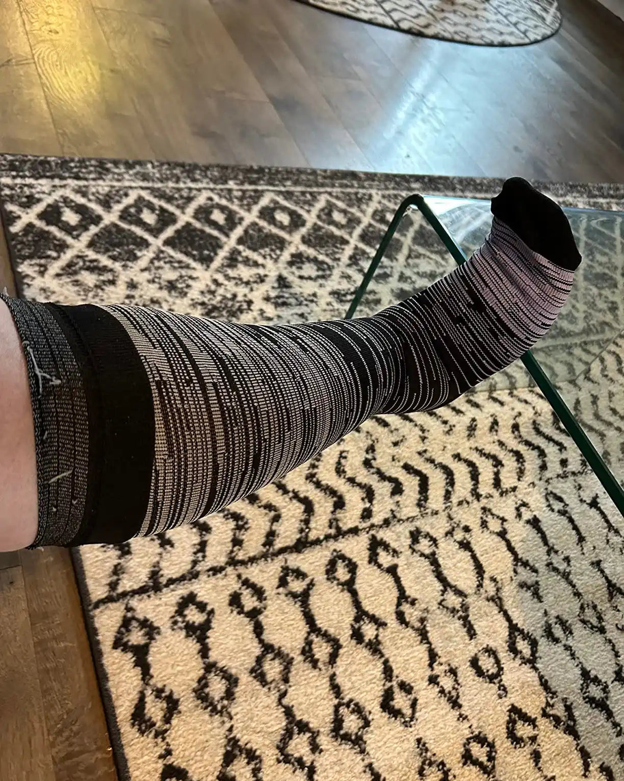 Une chaussette de compression bicolore noir et blanc à rayures.