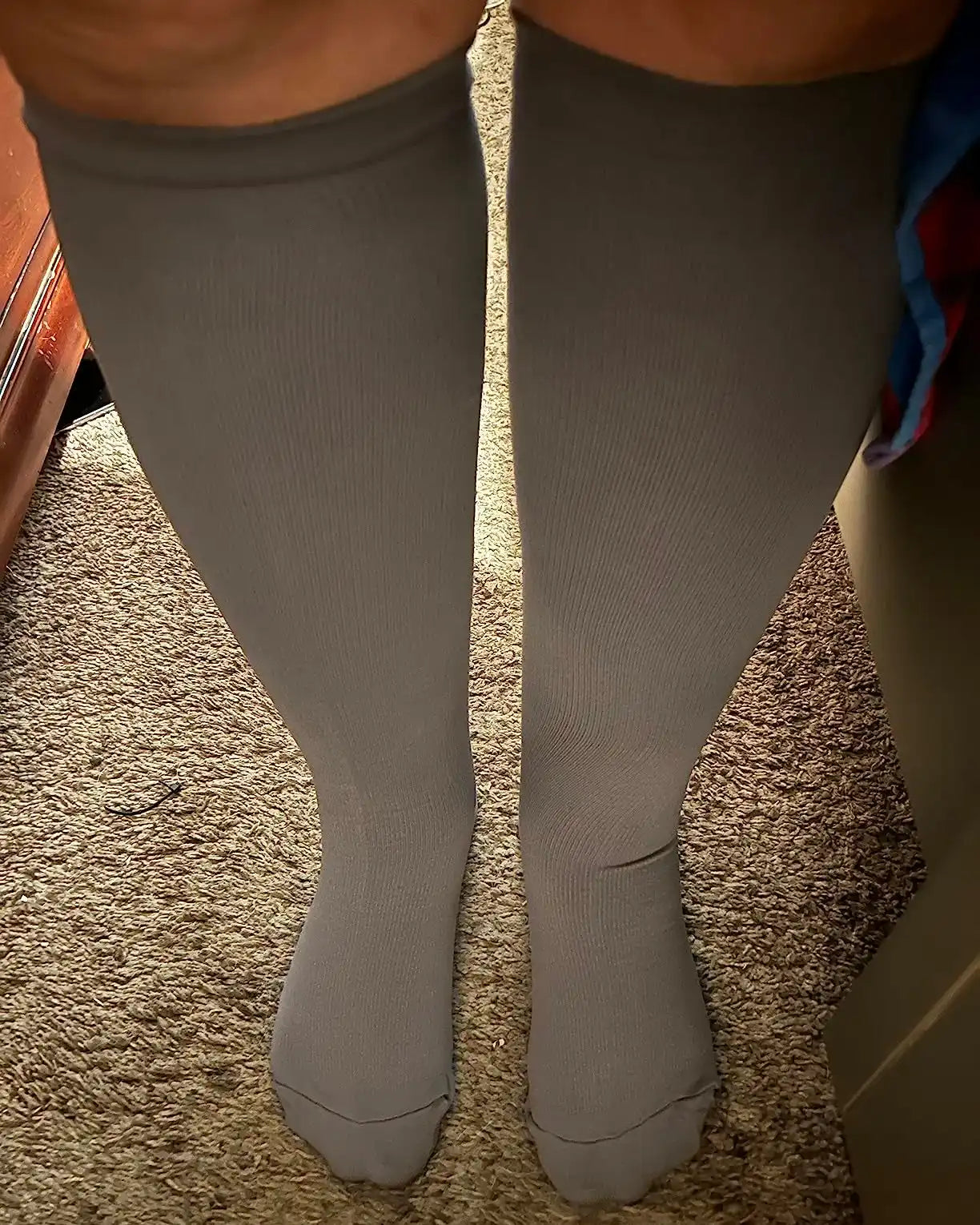 Une paire de chaussettes de compression gris foncé jusqu'aux genoux.