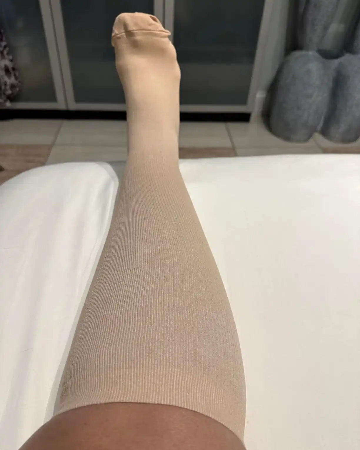 Une seule chaussette de compression beige avec un orteil ouvert.